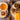One bowl of chaga mushroom tea, one bowl of honey with a wooden spoon, cinnamon sticks, and a yellow flower on a wooden surface.