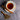 Teacup with floral saucer, cinnamon sticks, and a wooden spoon with tea leaves on a gray surface.