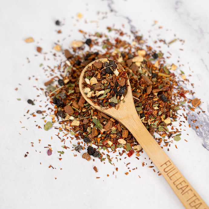 Wooden spoon of Organic Cold Remedy loose leaf tea on a white background.