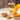 Glass of fenugreek tea with a wooden bowl and spoonful of fenugreek seeds on a wooden surface.