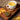 White mug of tea on a wooden tray with a bowl of tea leaves and autumn leaves.
