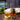 Tea set with glass mug, teapot, and tea leaves on a wooden table with a cozy background.