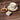 Cup of Slippery Elm tea in a floral teacup with gold accents on a wooden surface, accompanied by a small dish of powdered Slippery Elm bark and a bowl of honey with a honey dipper.