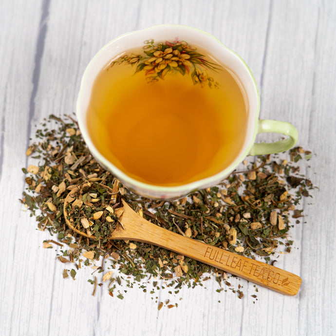 Tea cup with thyroid health tea and a wooden spoon on a light wooden surface