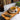 Tea cup with saucer on a wooden tray, surrounded by tea leaves and a teapot, with a blurred bookshelf in the background.