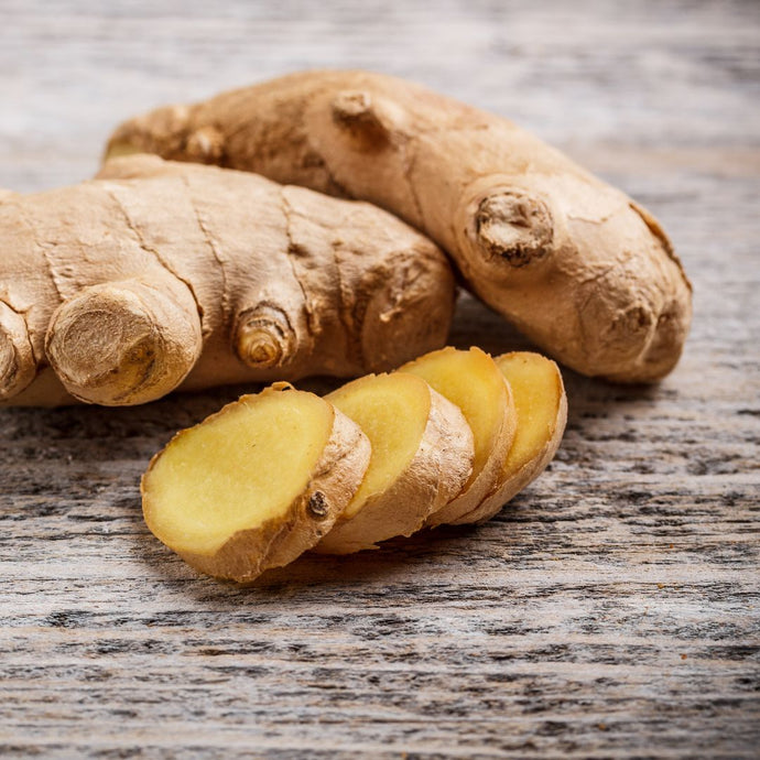 Whole and sliced ginger roots on a wooden surface