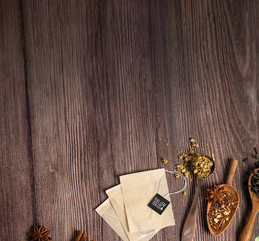 Assorted Full Leaf Tea Co. products with loose-leaf tea, cinnamon sticks, and tea bags arranged on a wooden surface.