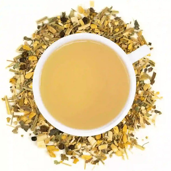 A cup of Organic Pain Relief Tea surrounded by dried herbs and spices including wild lettuce, mullein, turmeric, ginger, black pepper, lemongrass, and devil's claw.