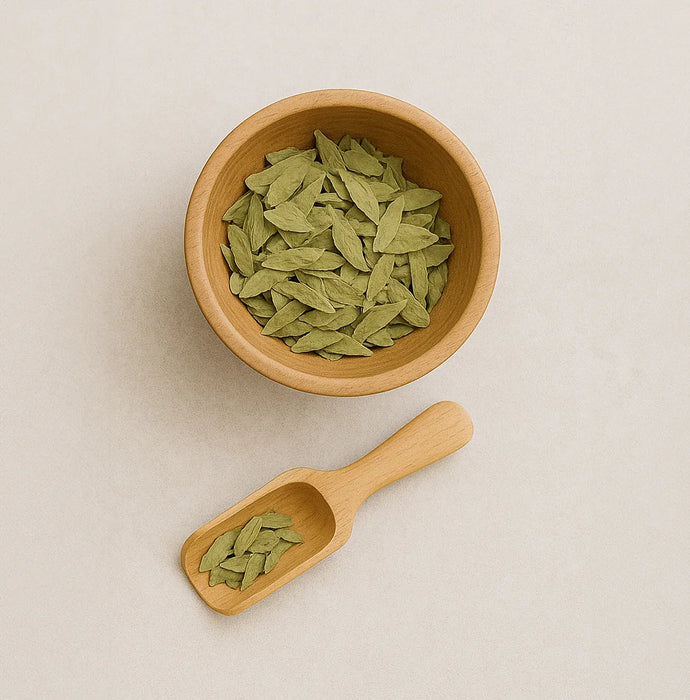 Wooden bowl and scoop filled with green leaves on a beige background