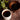 White cup of black coffee on a wooden table with a bowl of tea leaves and a plant.