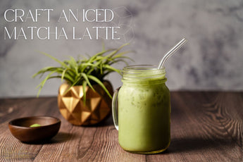 A refreshing iced matcha latte served in a mason jar with a glass straw, placed on a rustic wooden table. A small wooden bowl with matcha powder and a decorative plant in a geometric gold pot sit in the background. The text overlay reads 'Craft an Iced Ma