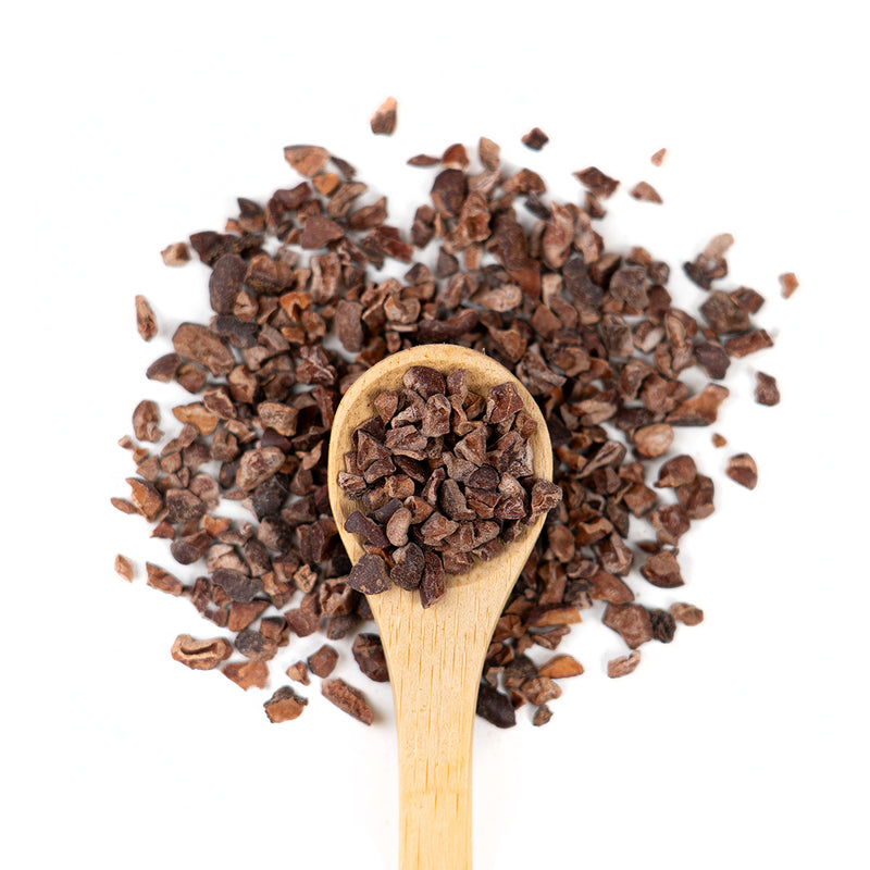 Wooden spoon of Organic Cacao Nibs on a white background.