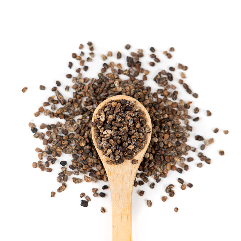 Wooden spoon of Organic Cardamom Seeds on a white background.