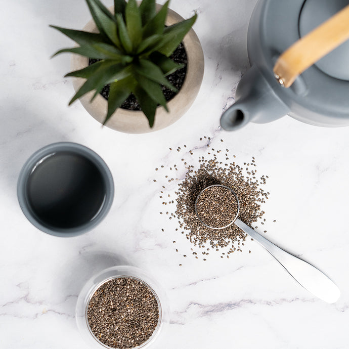 Chia seeds with a teapot, cup, and plant on a marble surface