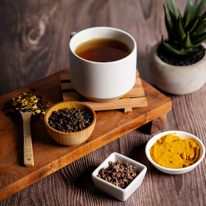 Circulation support tea in a white mug surrounded by it's ingredients. Objects are on a wooden table. 