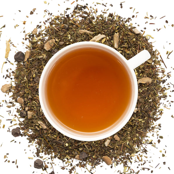 White cup of cortisol tea surrounded by dry cortisol tea herbs on a white background
