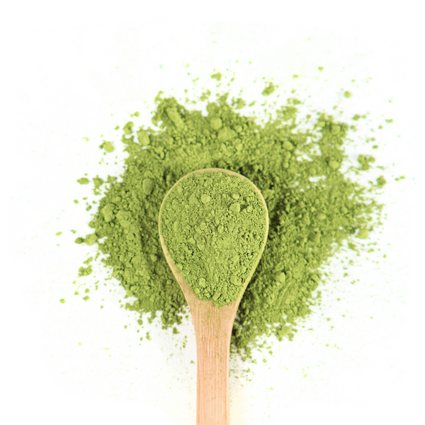 Wooden spoon filled with vibrant green matcha powder on a white background, with some powder scattered around.