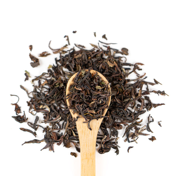 Wooden spoon of Organic Darjeeling on a white background.