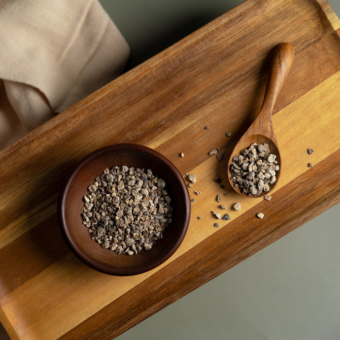 Wooden bowl and spoon with dried devil's claw on a wooden tray