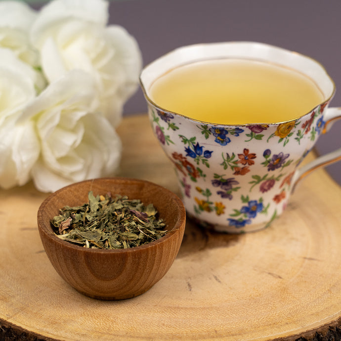 Tea cup with floral design and flowers, placed on a wooden surface.