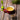 A red mug filled with freshly brewed epimedium tea on a rustic wooden surface, beside a glass bowl of dried epimedium leaves and a green leaf-shaped tea infuser.