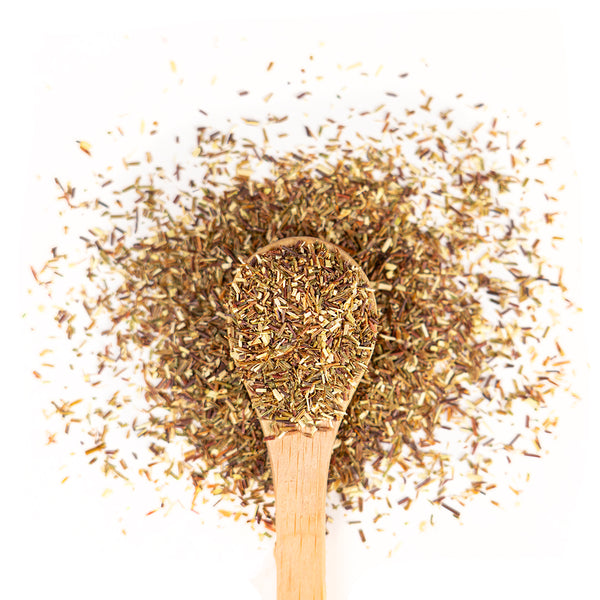 Wooden spoon of Organic Green Rooibos on a white background.