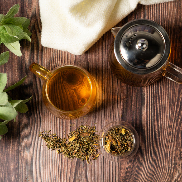 Tea cup, teapot, and tea leaves on a wooden surface