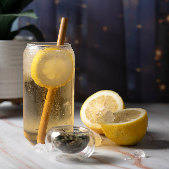 Glass of jade bliss with a straw, surrounded by lemons on a marble surface.