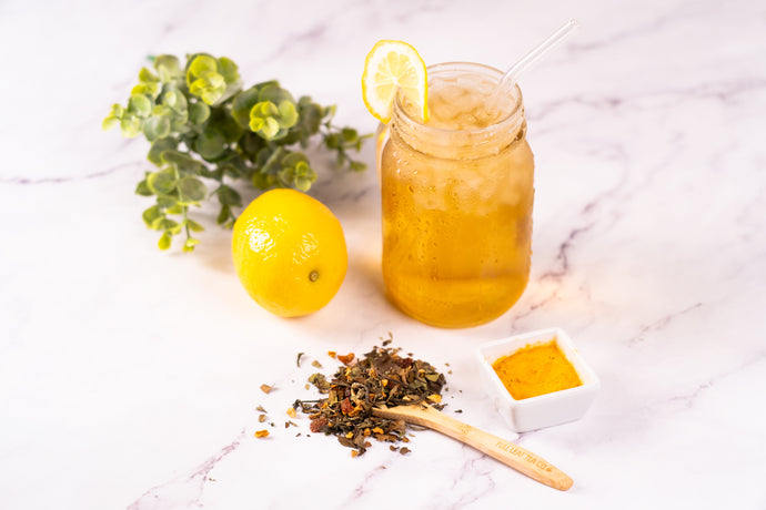Mason jar with iced tea, lemon, and turmeric on a marble surface