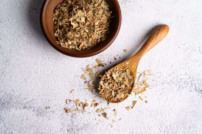 Dried linden leaf in a wooden bowl and spoon on a light surface