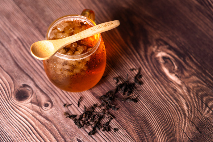 Glass of iced oolong with a gold spoon on a wooden surface