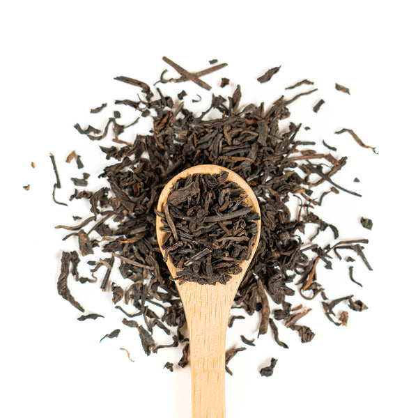 Wooden spoon of Organic Pu-Erh on a white background.