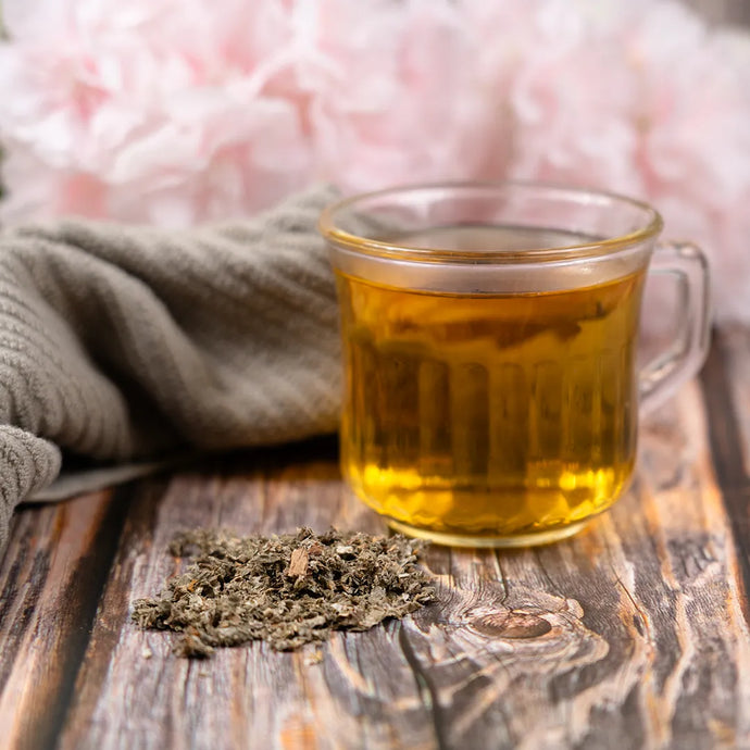 Glass cup of tea with raspberry leaves on a wooden surface