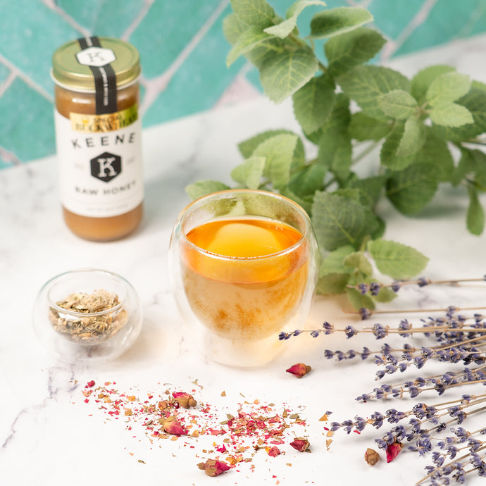 A tea cup surrounded by ingredients, honey, and decorations. 