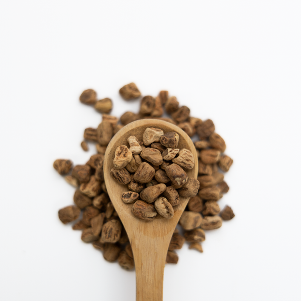 Wooden spoon filled with sarsaparilla on a white background