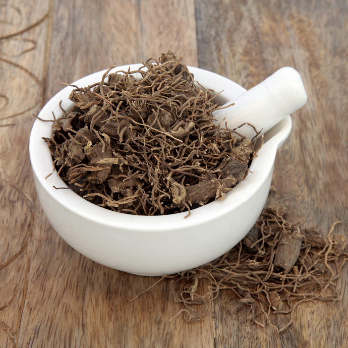 Dried black cohosh roots in a white mortar and pestle on a wooden surface.