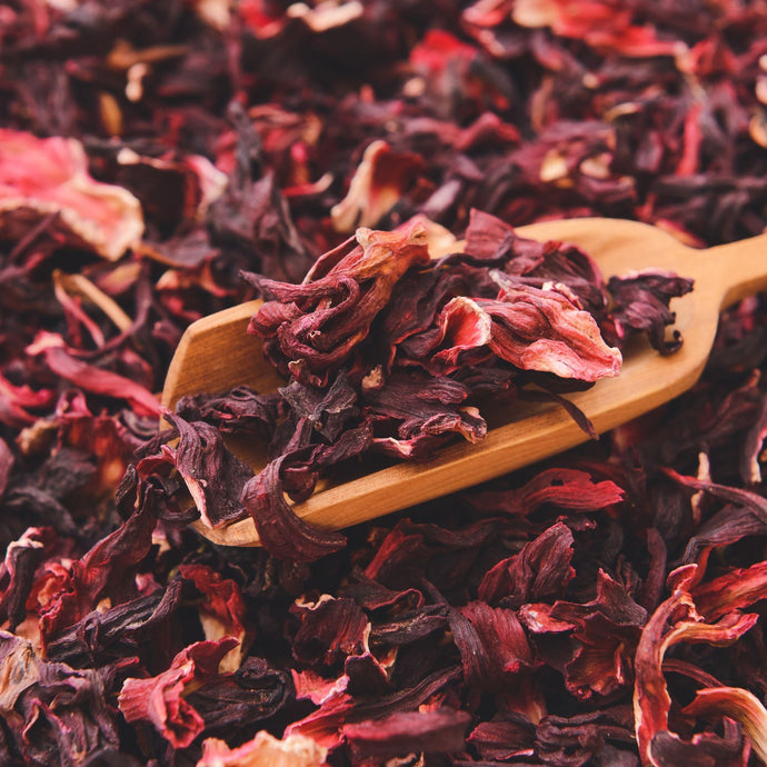 Dried hibiscus petals with a wooden scoop resting on top.