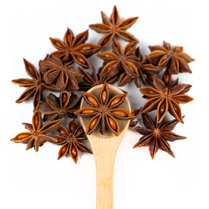 Wooden spoon of Organic Star Anise on a white background.