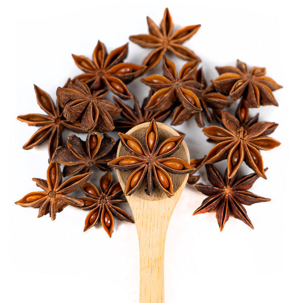 Wooden spoon of Organic Star Anise on a white background.