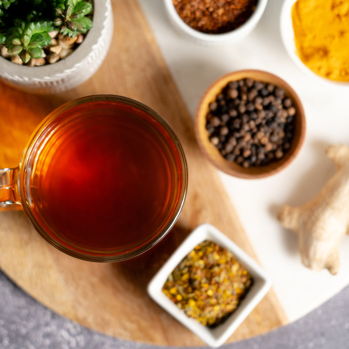 Tea cup with a selection of tea leaves and spices on a wooden board