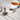 White teacup filled with vitex berry tea beside a small white bowl and metal spoon filled with dried vitex berries on a light wooden surface.