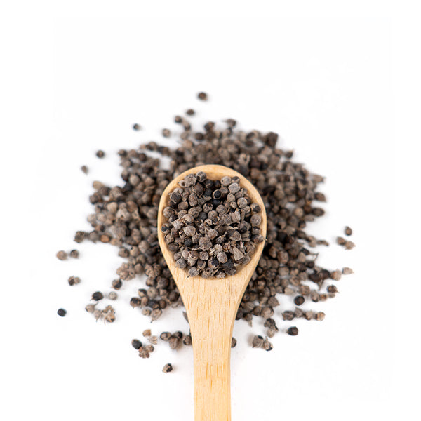 Wooden spoon of Organic Vitex Berries on a white background.