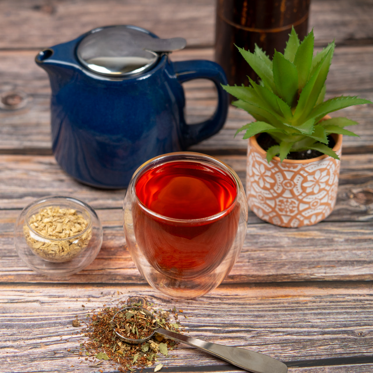 organic fresh start tea in glass mug with tea pot and loose leaf tea and succulent