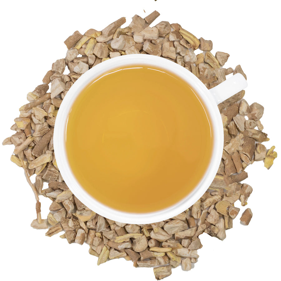 A white mug filled with Ashwagandha tea surrounded by ashwagandha