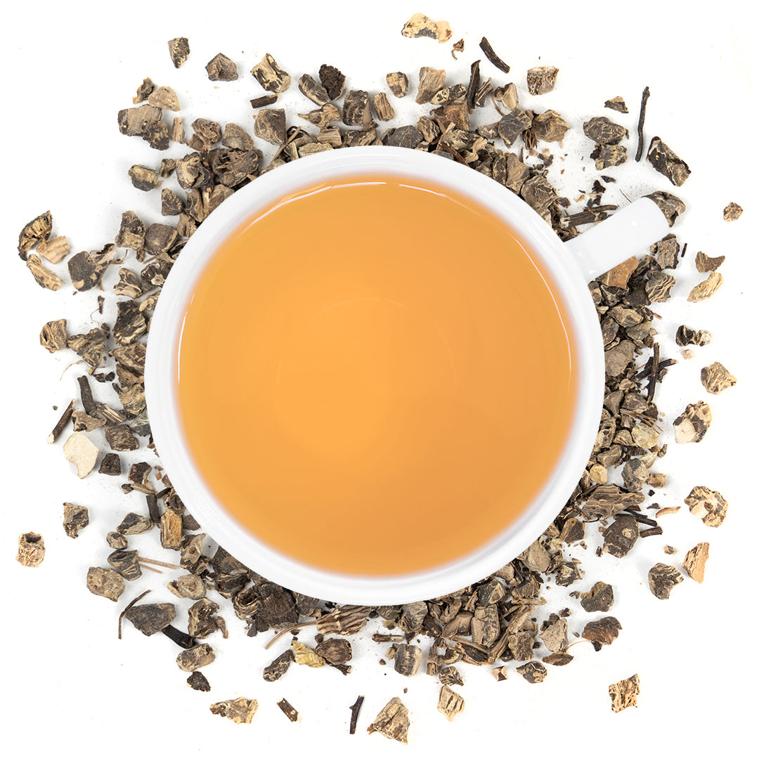 A white mug filled with black cohosh tea surrounded by cohosh