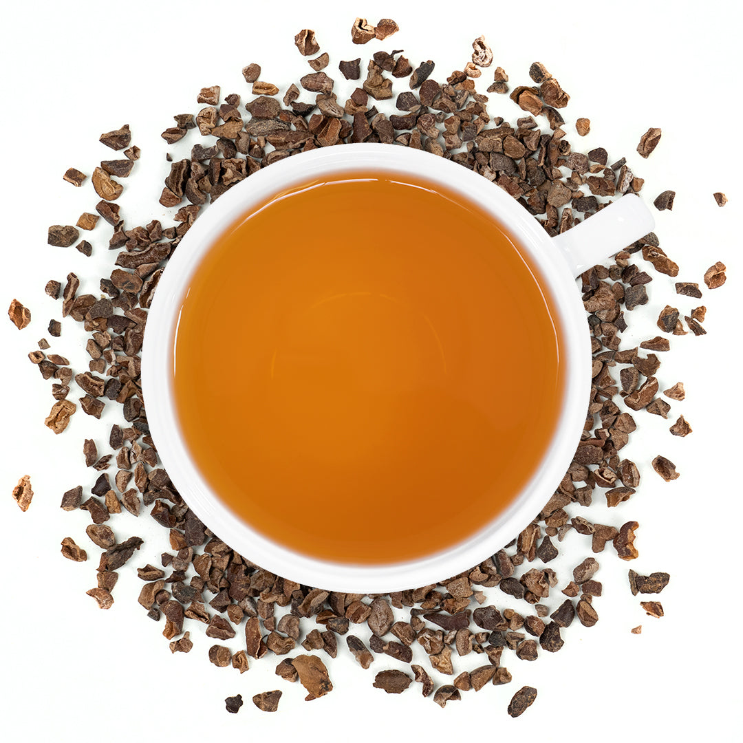 A white mug filled with cacao nibs tea surrounded by cacao nibs