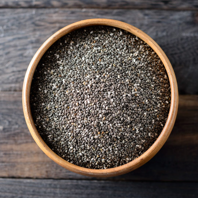 Wooden bowl filled with chia seeds on a wooden surface