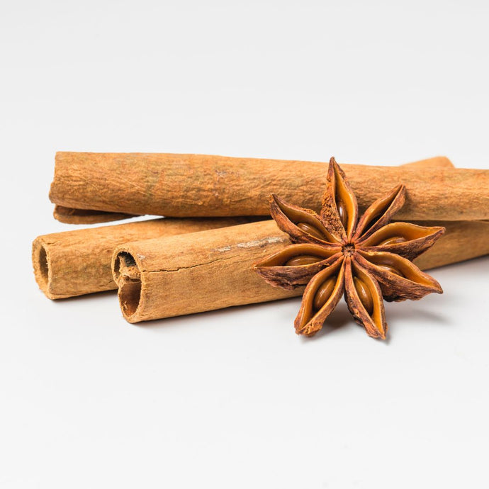 Three cinnamon sticks and a star anise on a white background