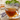 A clear mug with lavender tea and lavender next to it on a wooden surface. 