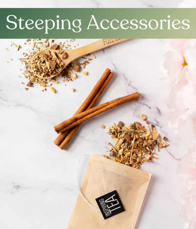 Loose leaf tea, cinnamon sticks, and a tea bag on a white surface, labeled 'Steeping Accessories.'